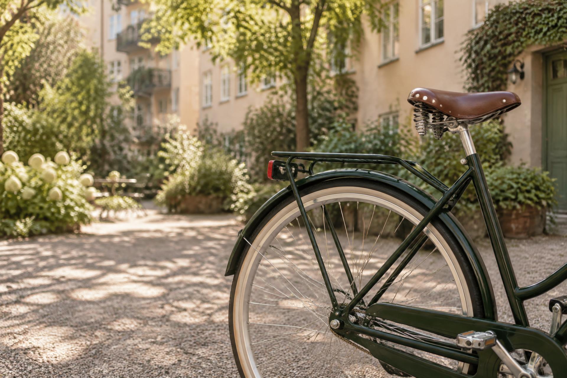 Mörkgrön cykel på en solig svensk bostadsgård